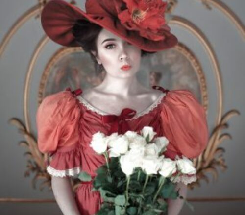 Portrait of a woman in an elegant red hat and dress, holding white roses, showcasing the art of portrait photography. Artisan Boudoir Portrait